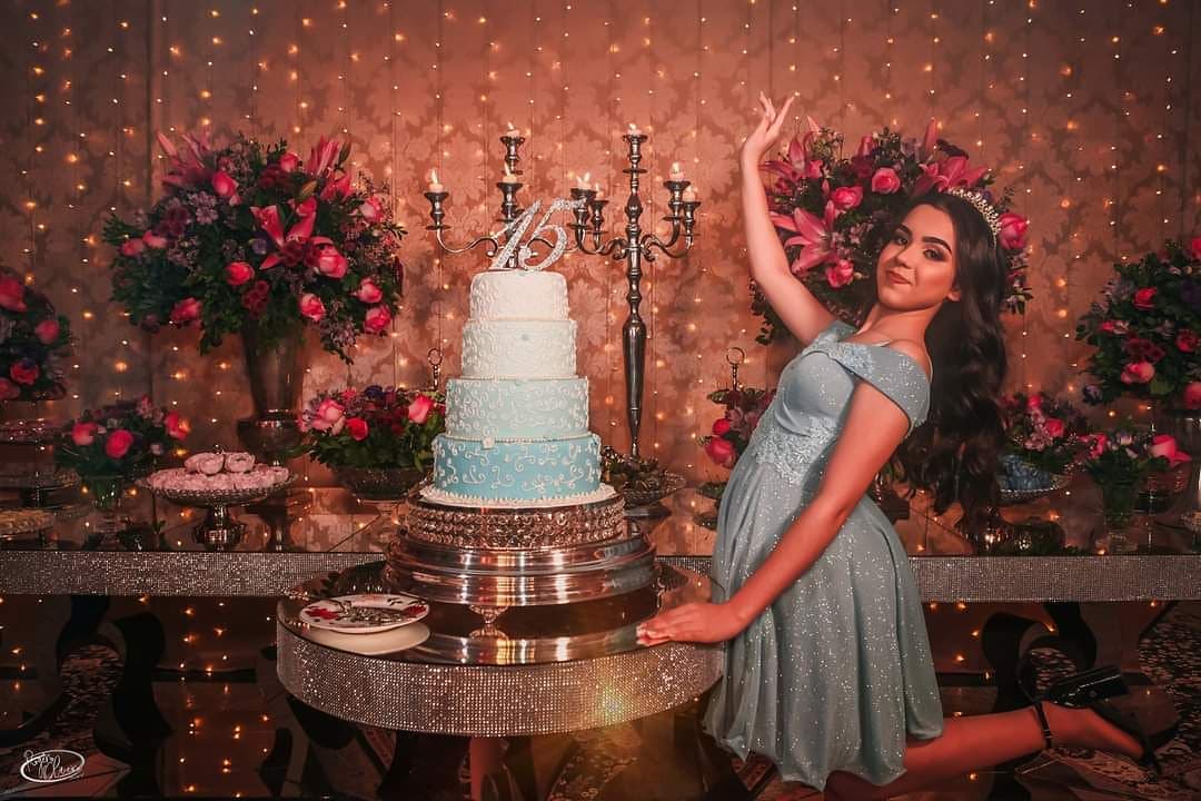 Debutante ao lado do bolo de quinze anos